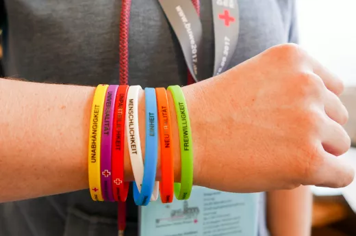 Armbänder mit den 7 Rotkreuzgrundsätzen an einem Arm