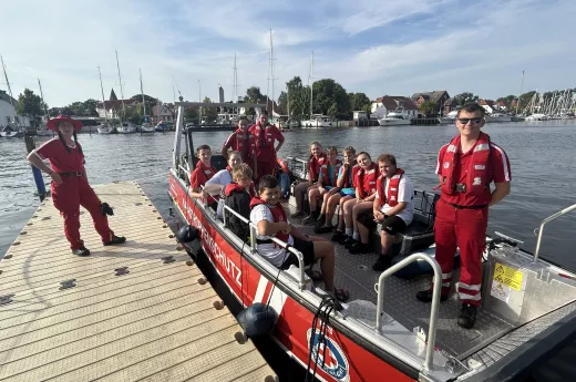 Teilnehmende des JRK-Ferienlagers 2024 mit ehrenamtlichen Einsatzkräften des Wassergefahrenzugs Greifswald